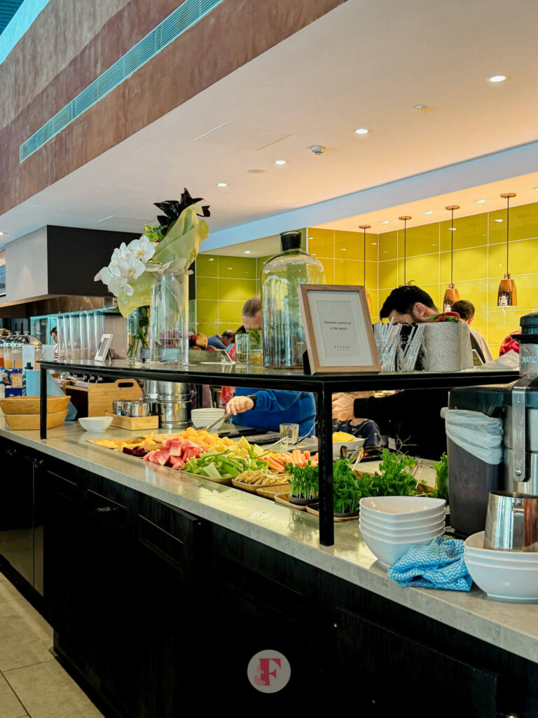 A vibrant fruit and salad bar at the Rydges Hunter Valley breakfast buffet, offering fresh produce and greens with a bustling dining area in the background.