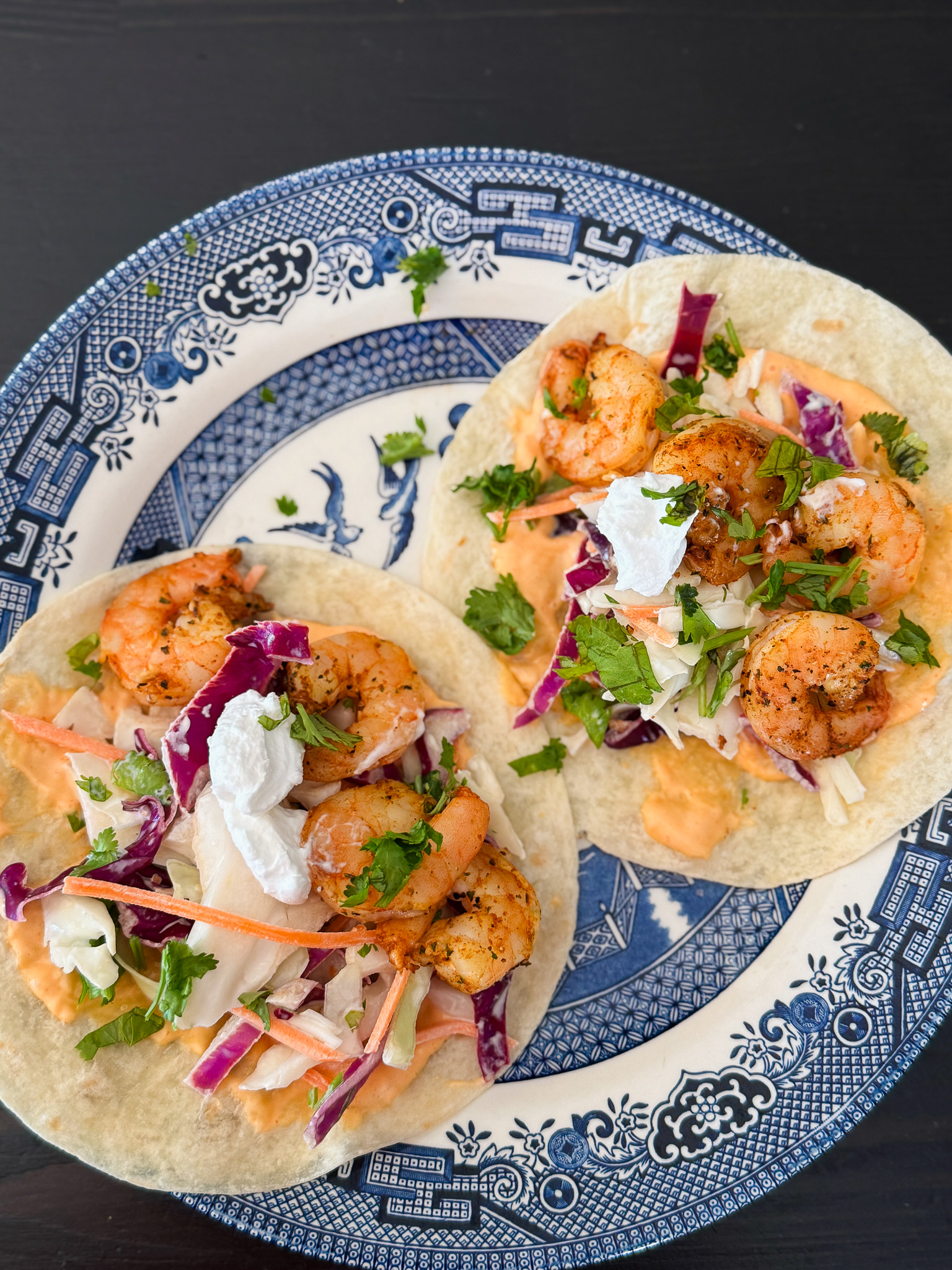 Overhead shot of shrimp tacos with condiments and veggies