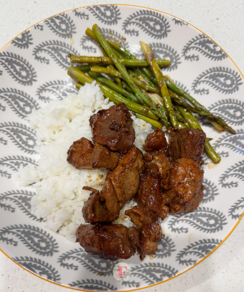 A shot of pork adobo, rice, beans, in a white bowl